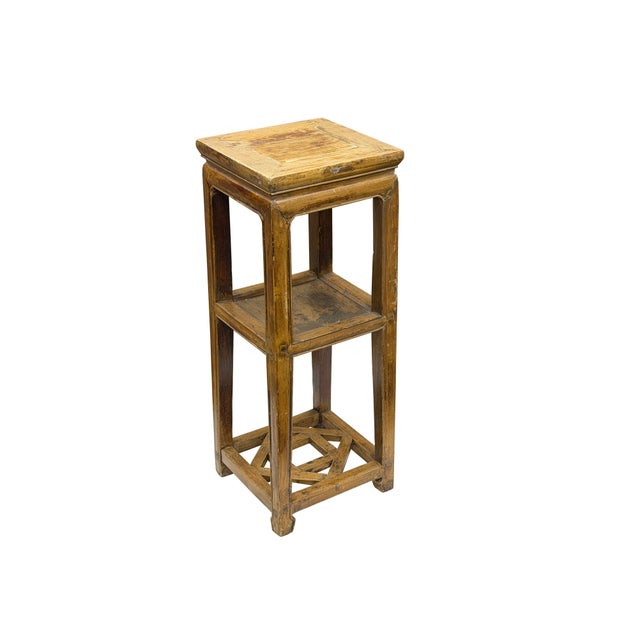This tall, square display stand is crafted from wood with a weathered, honey-brown patina that highlights its rustic...