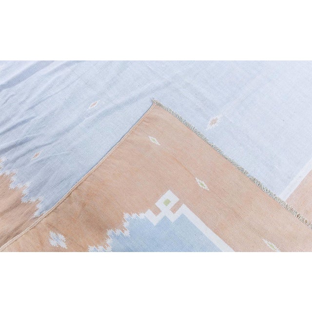 This vintage 1945 Indian Dhurrie rug presents a serene and sophisticated interpretation of traditional flat-weave design,...