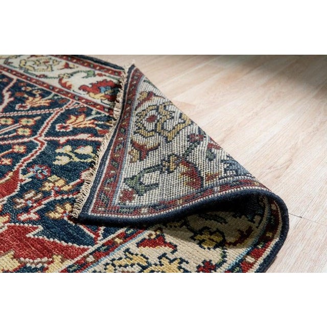 This blue wool rug features a traditional hand knotted pile weave. Produced in India, the rug presents a solid...
