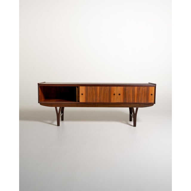 Scandinavian-made teak sideboard from the 1960s, featuring two sliding doors and three central drawers. The front features...