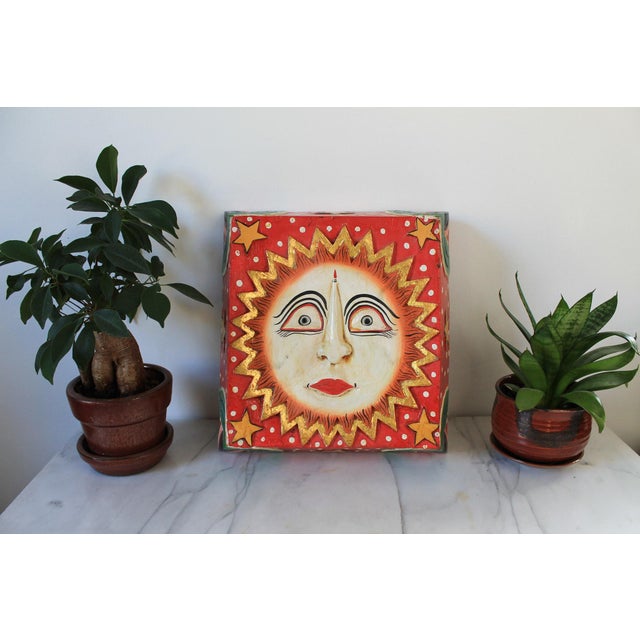 Vintage handcrafted, painted wooden sun face wall hanging or plaque featuring a prominent central sun face with a red and...