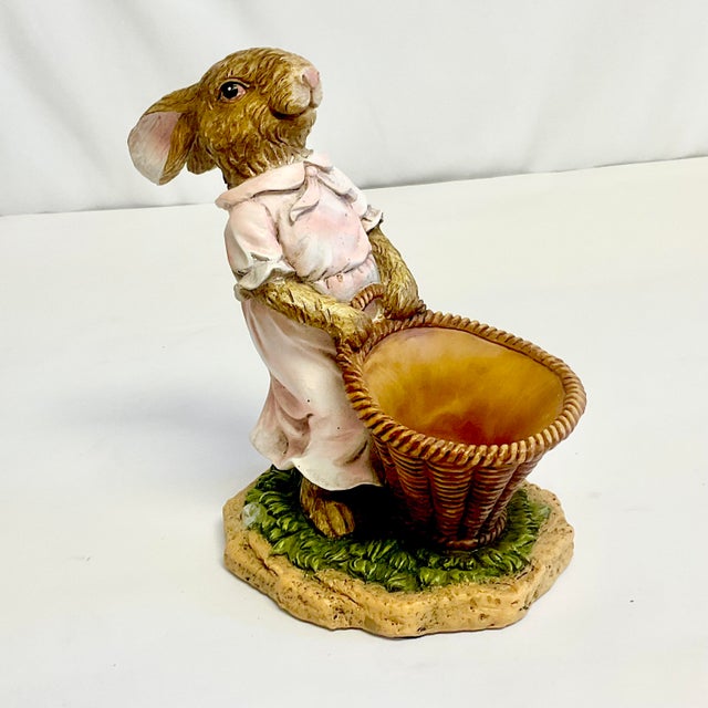 This is a whimsical Girl Bunny in a pink dress pulling a a large basket that is a planter for a small botanical. She is a...