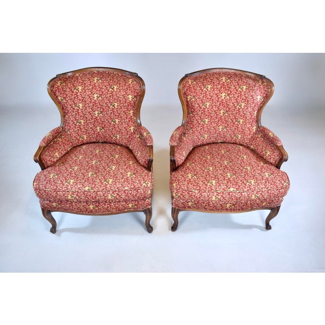 A lovely, solid pair of carved Walnut Bergere chairs in whimsical raised trunk elephants upholstery. Nicely maintained all...