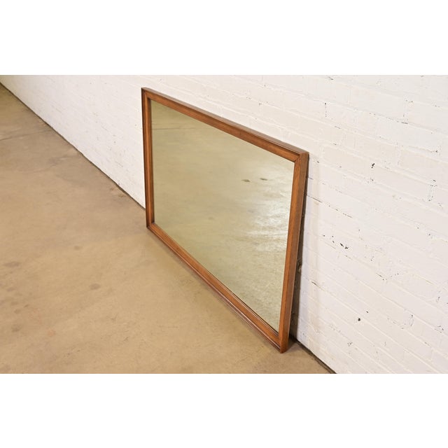 A gorgeous Mid-Century Modern walnut framed large wall mirror By Drexel USA, 1964 Measures: 53.25"W x 1.75"D x 33.25"H....