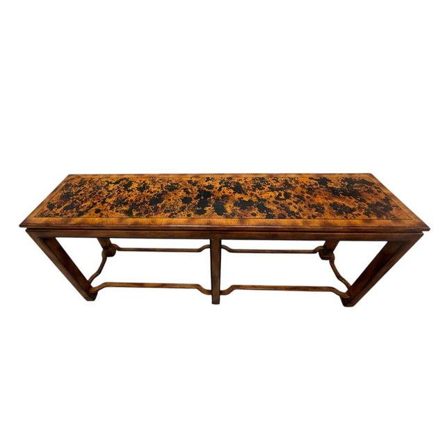 An Asian inspired wood console table distinguished by its rich faux tortoise shell painted top, offering a warm, mottled...