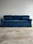 Vintage three-seat sofa upholstered in rich blue corduroy, with rolled arms, a tailored skirt, and a long, low profile....