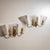 Pair of wall lights with loop-shaped brass mounts and conical clear glass shades featuring diagonal ribbed decoration....