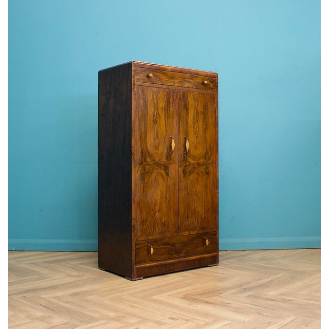 A 1930s Art Deco compact gentleman’s wardrobe with bookmatched walnut veneer to the twin doors, forming a mirrored grain...