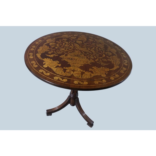 Wonderfully crafted circular flip top table with a floral motif surrounding a Roman antiquity style vase and a bird in...