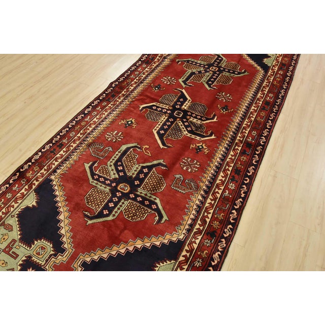 An authentic vintage tribal Karajeh runner hand-knotted with fine wool and natural dyes. This nomadic rug features three...