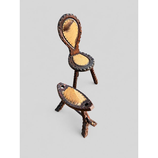A beautifully designed three-legged chair with a matching footrest, made from dark-stained pine and upholstered in...
