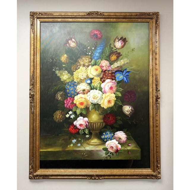 This large original oil on canvas presents a lush floral arrangement overflowing from a classical urn, with richly layered...