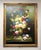 This large original oil on canvas presents a lush floral arrangement overflowing from a classical urn, with richly layered...