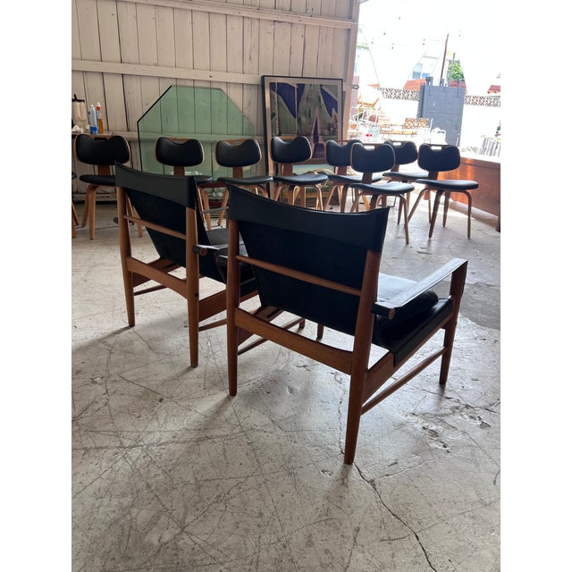 Pair of mid century Swedish sling style lounge chairs, featuring newly upholstered soft black leather, and refinished teak...