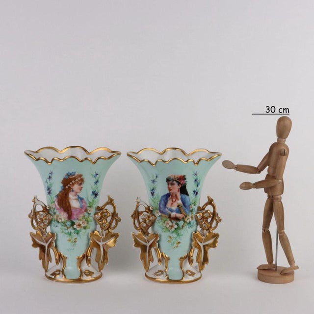 Pair of porcelain bouquet vases with golden decorations with plant motifs. In the center, female bust surrounded by...
