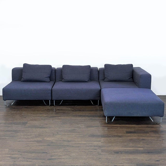 This CB2 sectional sofa features a sleek modern design with dark blue fabric and chrome metal legs. It includes three...