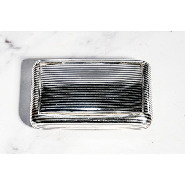 This handsome antique silver niello snuff box is a sophisticated example of traditional metalworking artistry, combining...