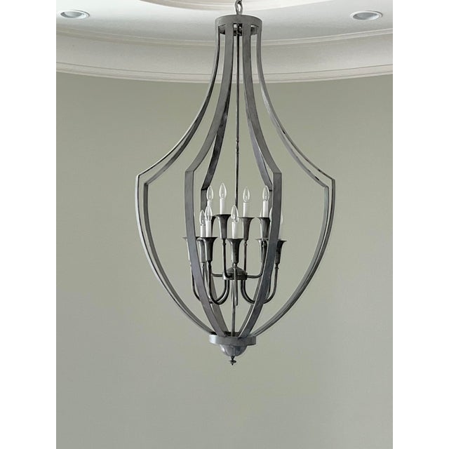 A striking large-scale chandelier featuring a sculptural open-frame silhouette and an elegant silver-tone finish....