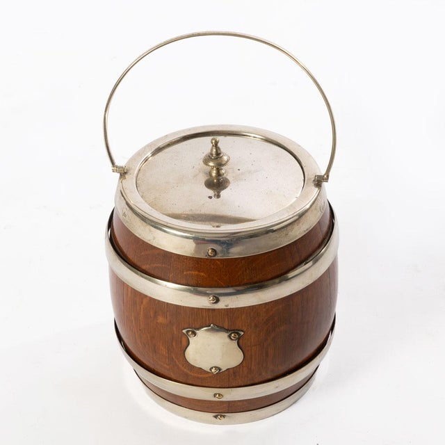 English oak Edwardian biscuit barrel with silver plated accents, porcelain liner and a shield shaped cartouche.