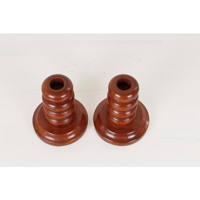 Pair of vintage turned wood candlesticks with stacked ring stems on a wide bases in warm reddish-brown and a sheen finish....
