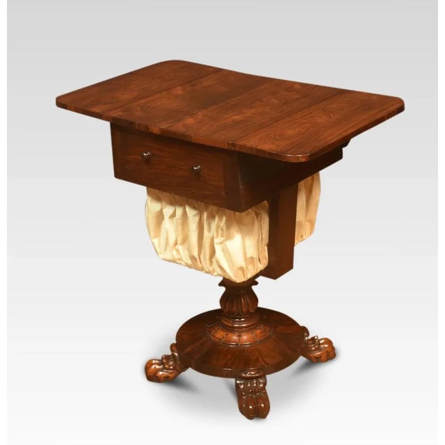 Rosewood sewing table, the well-figured top with lift-up ends above two frieze drawers with knob hands to the upholstered...