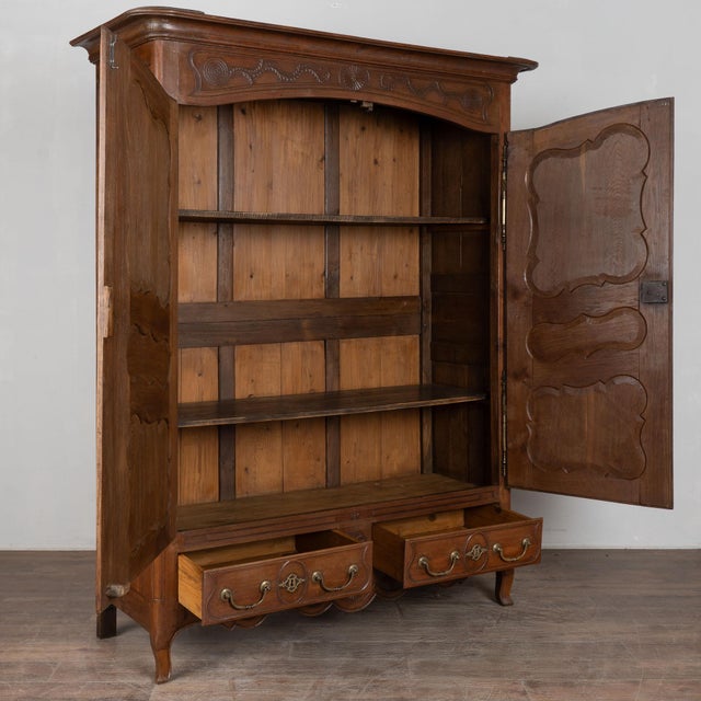 19th century French armoire, crafted in oak with accents of pine and detailed with decorative inlay throughout the two...