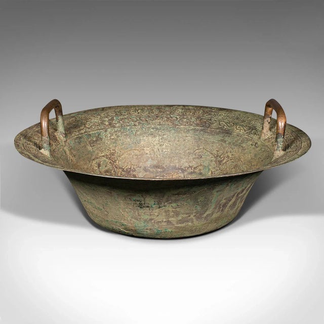 This is an antique ceremonial bowl. A Chinese, patinated brass twin handled dish, dating to the late Victorian period,...