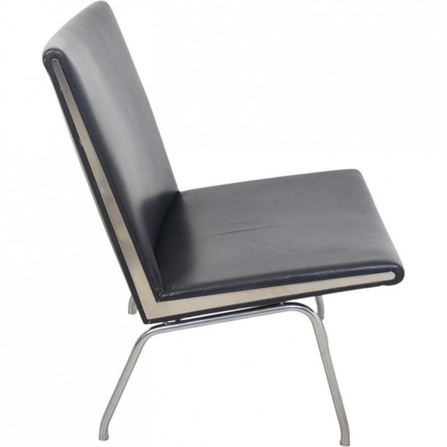 Hans wegner ap40 lounge chair upholstered in black leather, with a steel frame. The chair is from around the 1990s and...