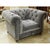 Upholstered in soft gray fabric, this classic design features deep button tufting across the back and arms with rolled...