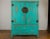 A Chinese Qing Dynasty period cabinet from the 19th century with custom distressed blue green lacquer, carved apron and...
