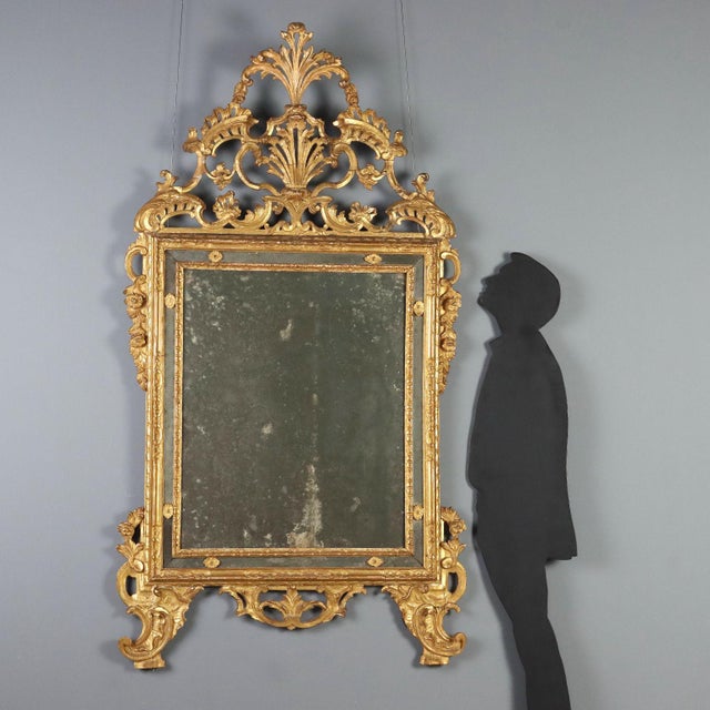Wall mirror in carved and gilded limewood, featuring a rectangular frame housing the central mirror, surrounded by a...