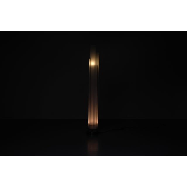 "Adubai" floor lamp. It rests on a cylindrical steel base adorned with seven opal glass panels of varying sizes. It is...