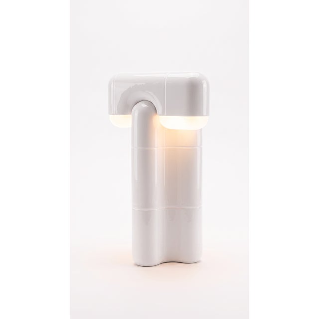 Part light, part totem. This tall table lamp stacks the collection's curved-tile module into a slender column that draws...