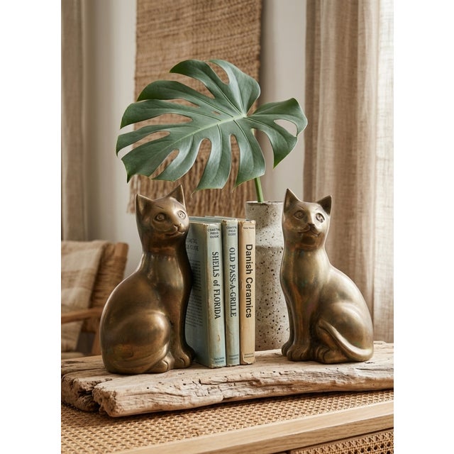 A striking and exceptionally substantial pair of vintage solid brass sitting cat sculptures. Reaching nearly 9 inches in...