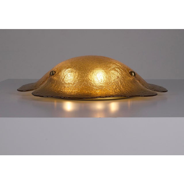 Large amber Murano glass ceiling light, featuring a convex shape with three lobes and a solid brass fitting. Equipped with...