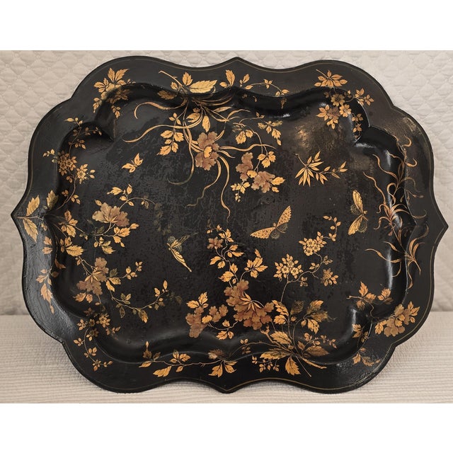 Large scalloped-edge metal tray finished in a black japanned ground and decorated with hand-painted gilt florals,...