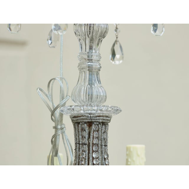A French four-light chandelier from circa 1920 with curving arms, faceted crystals and beaded strands. This exquisite...