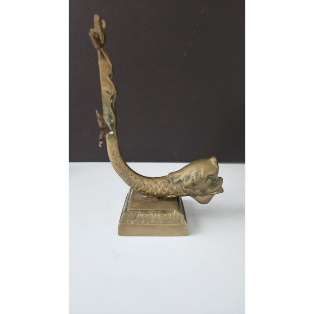 An early 20th-century solid brass figural bookend featuring a sculptural botanical form with a twisting vertical stem and...