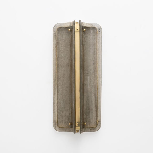 An elegant pair of italian big sconces composed of curved and fluted murano glass panels in a refined shade of smoked. The...