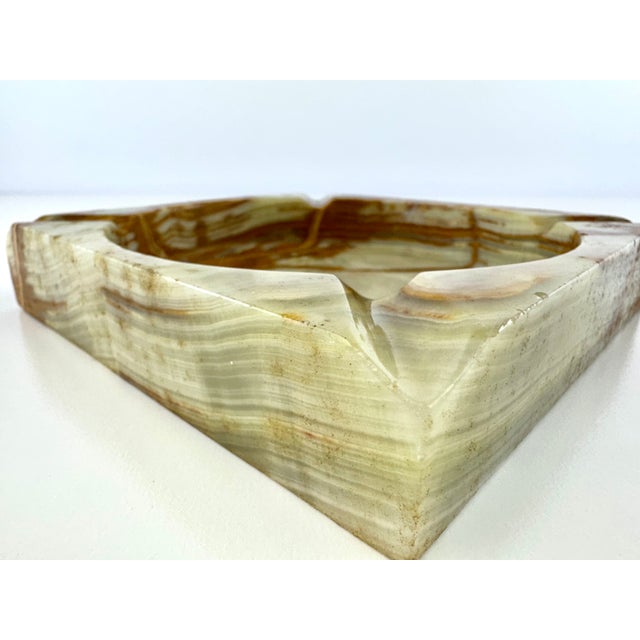 A substantial vintage carved onyx ashtray featuring dramatic natural banding in warm caramel, cream, amber and soft gray-...