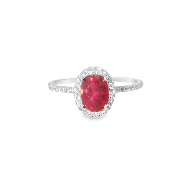 Elegant 14K white gold cocktail ring featuring one natural oval ruby nearly 1 carat surrounded by brilliant round diamonds...