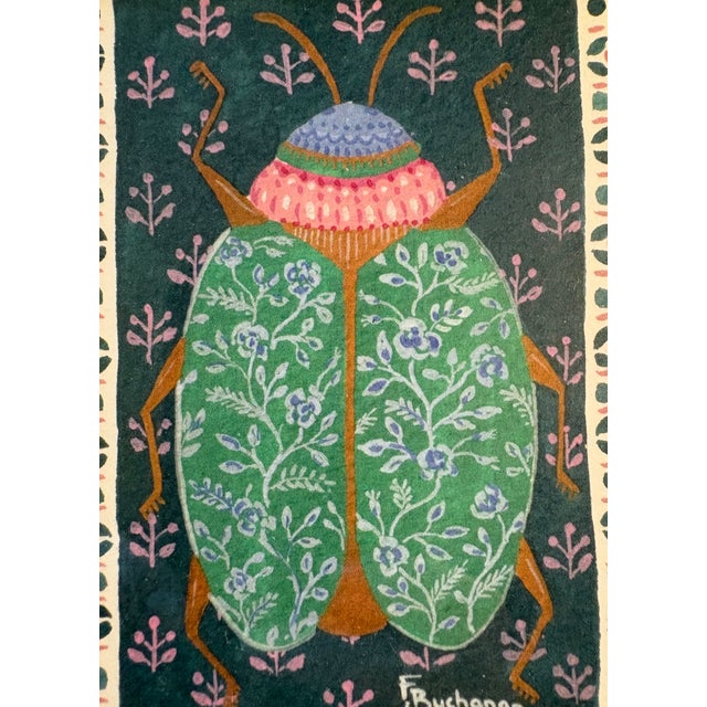 Colorful beetle with floral design shell against bohemian-patterned background on heavy cotton paper under glass in a...