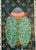 Colorful beetle with floral design shell against bohemian-patterned background on heavy cotton paper under glass in a...