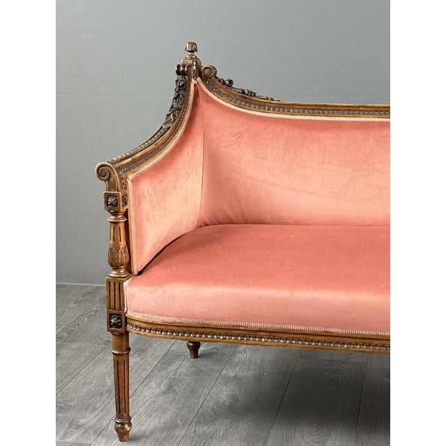 Elegant Louis XVI style sofa in carved and molded wood resting on fluted, tapered legs. The gently curved back and console...