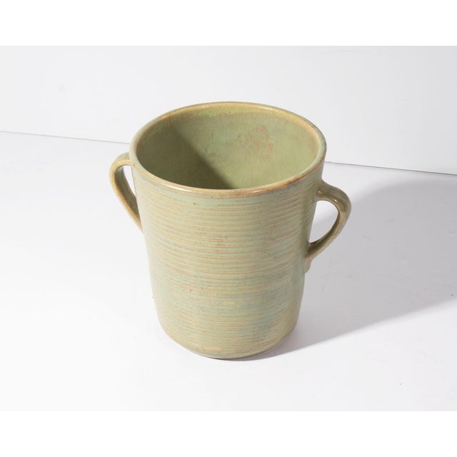 A vase by Monmouth Western Stoneware. This vase has a ribbed exterior and double handles. The underside is marked with the...