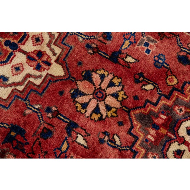 Beautiful vintage Persian Heriz hand-knotted wool runner with a red color field. This piece has a brown frame and...