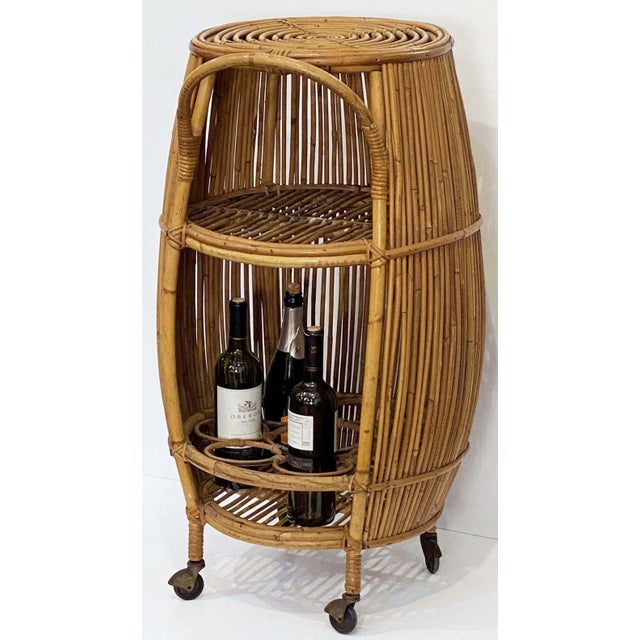 A fine Italian bar cart or trolley in rattan and bamboo from the 1960s, featuring a barrel-shaped design with curved...