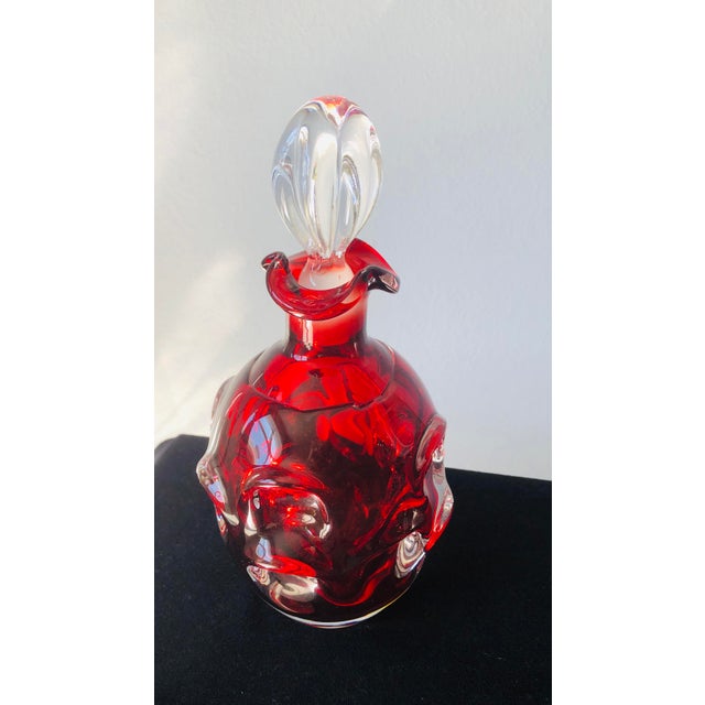 This striking mid-century art glass decanter features rich ruby-red hand-blown glass accented with applied clear glass...