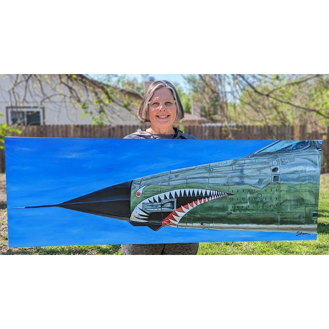 The artwork features the nose of a F105G Thunderbird, showcasing its striking shark mouth design against a vibrant blue...