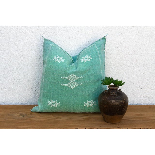 A framed border and two stacked bowtie-diamond medallions anchor the center of this handcrafted Moroccan cactus silk...